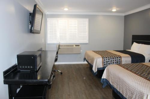 a hotel room with two beds and a desk with a tv at ERTH INN by AGA Los Angeles in Los Angeles