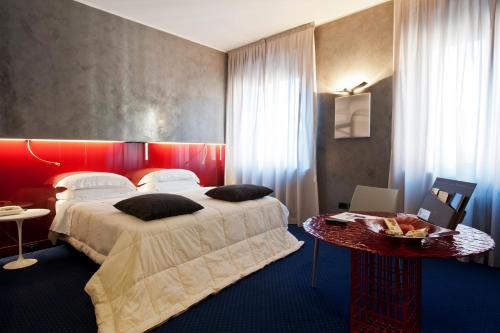 a bedroom with a bed with a red headboard and a table at Rechigi Hotel - Adults Only in Mantova