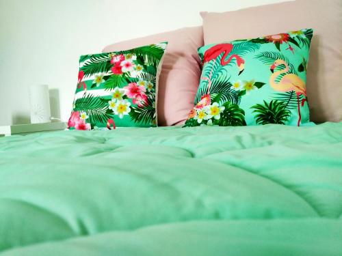 a bed with green sheets and two pillows with flowers at Casa da Serra in Nazaré