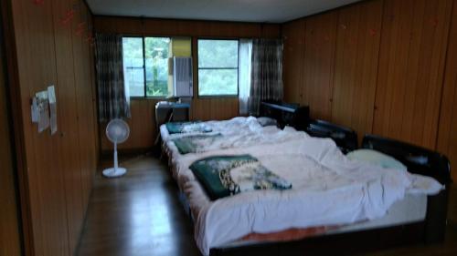 1 dormitorio con 2 camas grandes con sábanas blancas en Guesthouse Taihei, en Aso