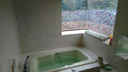a bath tub in a bathroom with a window at Guesthouse Taihei in Aso