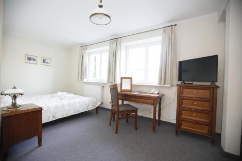 a bedroom with a bed and a desk and a television at Leśniczówka Nibork in Nidzica