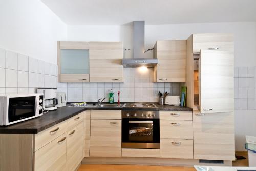 a kitchen with wooden cabinets and a microwave at Top Apartmentwohnungen Veltins Arena in Gelsenkirchen