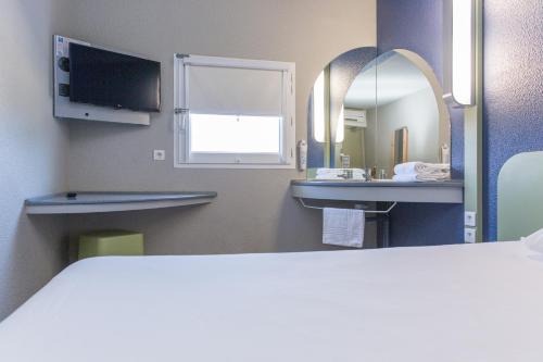 a bathroom with a bed and a sink and a mirror at Ibis Budget Sisteron in Sisteron