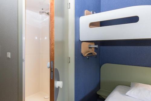 a small bathroom with a bed and a shower at Ibis Budget Sisteron in Sisteron