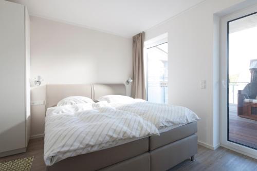ノルダーナイにあるDeluxe Suite Kleine weiße Düne (mit West- u. Ostbalkon)の白いベッドルーム(ベッド1台、窓付)