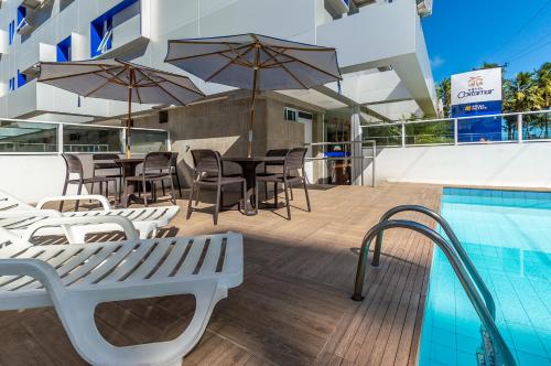 a patio with tables and chairs next to a swimming pool at Hotel Costamar Ponta Verde in Maceió