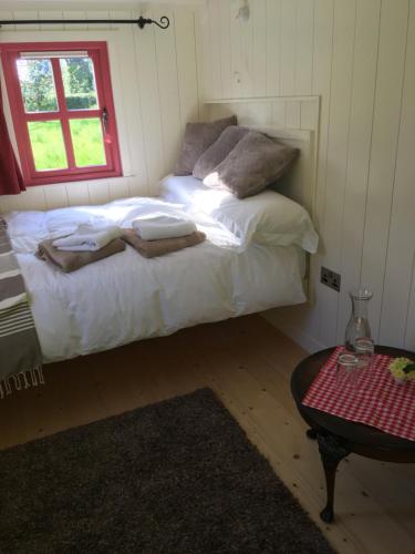 a bedroom with a bed with white sheets and a window at Blackstairs Shepherds Huts in Killedmond