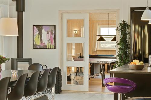a kitchen and dining room with a table and a piano at Luksus-poolhus L21 in Harboør