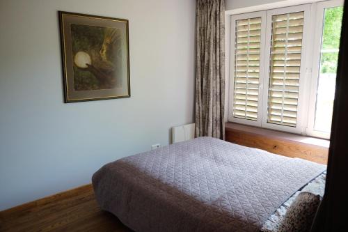 a bedroom with a bed and a picture on the wall at Amber White apartment in Juodkrantė