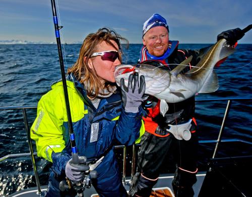 a man and a woman on a boat with a fish at Lyngen Experience Lodge in Nord-Lenangen