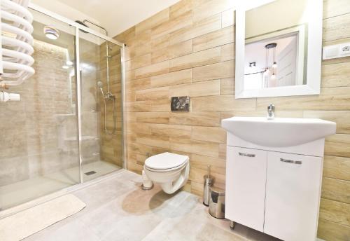 La salle de bains est pourvue de toilettes, d'un lavabo et d'une douche. dans l'établissement Metropolis Apartment, à Toruń