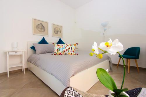 een slaapkamer met een wit bed met een witte bloem bij Le Casette di Marcì in Palermo