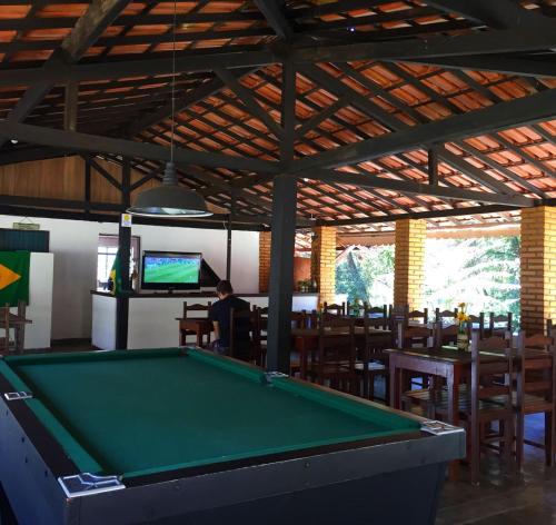 einen Billardtisch in einem Restaurant mit einem Mann, der TV sieht in der Unterkunft Pousada Cantinho do Mundo in Brumadinho