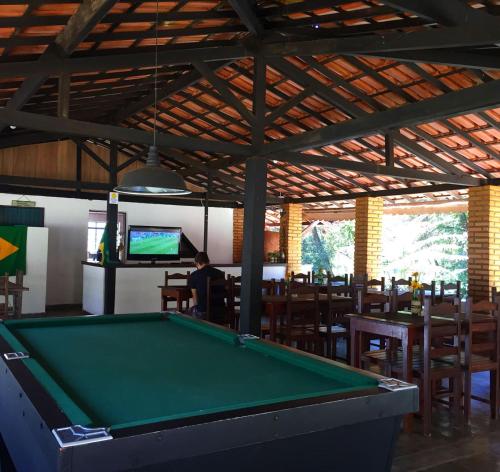 a pool table in a restaurant with a man watching tv at Pousada Cantinho do Mundo in Brumadinho