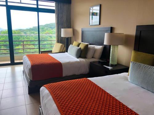 a hotel room with two beds and a balcony at Summit Rainforest Golf Resort & All Inclusive in Paraíso