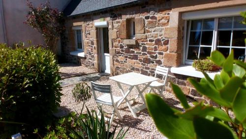 deux chaises et une table devant un bâtiment dans l'établissement Ty Jeanne, le charme de la pierre au coeur du village, à Plougasnou