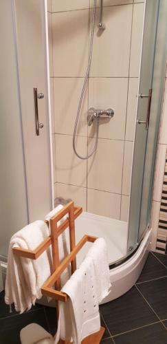 a bathroom with a shower with a wooden chair at City Inn Apartment in Osijek