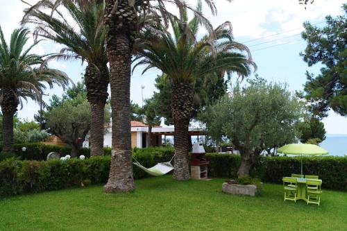 a yard with palm trees and a hammock and a house at Halkidiki Trikorfo Luxury Maisonette in Gerakini