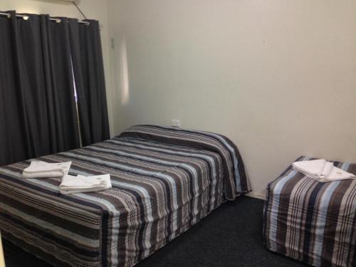 a bed room with two beds and a desk at The Metropolitan Hotel in Mackay