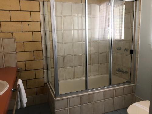 a shower with a glass door in a bathroom at True Blue Motor Inn in Rockhampton