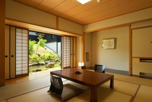 a room with a table and chairs and a window at Hotel Kikori in Hida