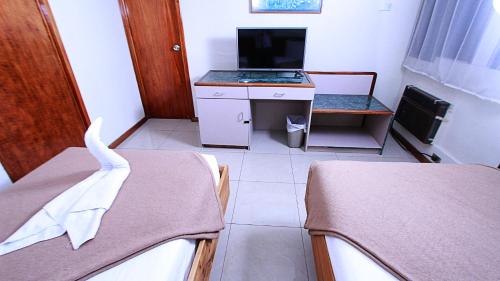 a room with two beds and a desk with a television at Hotel Ambassador in San José