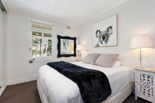 a white bedroom with a bed with a black blanket on it at Pyrmont Self-Contained Terrace House (64 BUL) in Sydney