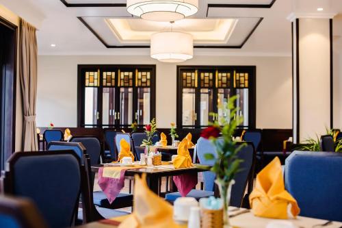 a dining room with tables and blue chairs at Laluna Hoi An Riverside Hotel & Spa in Hoi An