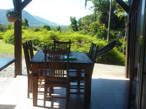 a dining table and chairs on a porch with a view at Daintree Holiday Homes - La Vista in Cow Bay