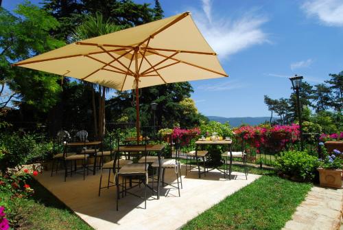 a patio with tables and chairs and a large yellow umbrella at Torre Sangiovanni Albergo e Ristorante da Rosary in Todi