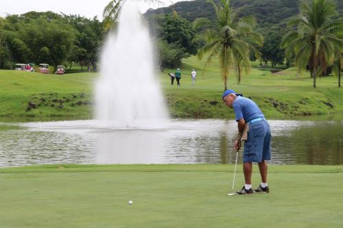 a man playing golf in front of a fountain at Summit Rainforest Golf Resort & All Inclusive in Paraíso