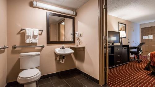 a bathroom with a toilet and a sink and a desk at Best Western Van Buren Inn in Van Buren