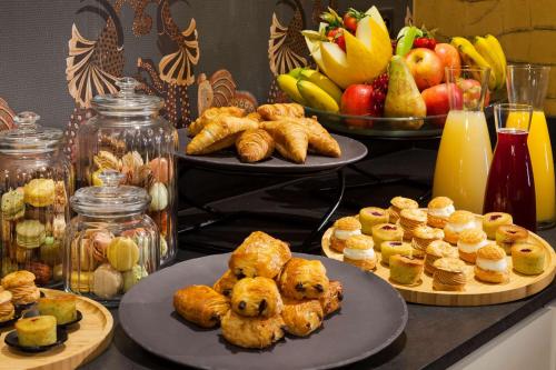 una mesa cubierta con platos de comida y fruta en Hotel Inn Paris CDG Airport, en Roissy-en-France