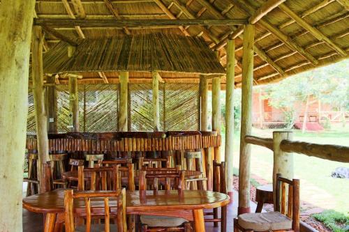 a restaurant with wooden tables and chairs in a pavilion at Bushbaby Lodge in Mukono