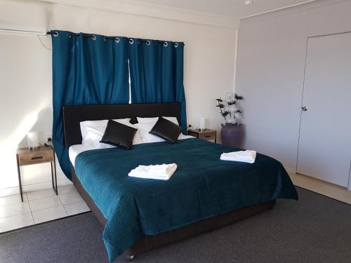 1 dormitorio con 1 cama grande con manta azul en The Q Motel Rockhampton, en Rockhampton