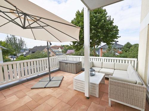 a patio with a couch and an umbrella on a balcony at Wohnpark Stadt Hamburg in Binz - WG 54 in Binz
