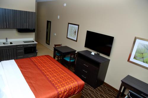 a hotel room with a bed and a flat screen tv at Americas Best Value Inn & Suites-Prairieville in Prairieville 