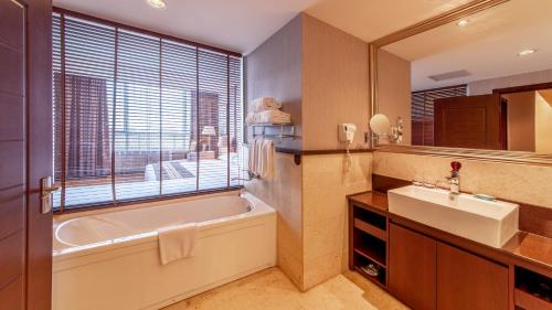 baño con bañera, lavabo y ventana en Beijing Sunflower Hotel en Tongzhou