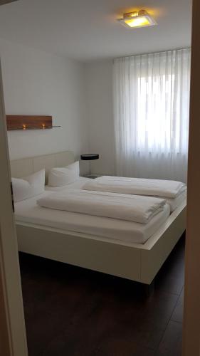 um quarto com 2 camas com lençóis brancos e uma janela em Wellness- & Golf-Appartement 4.4 Hebelhof em Bad Bellingen
