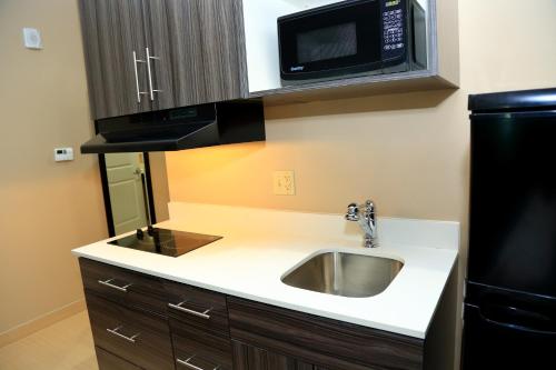 a kitchen with a sink and a microwave at Americas Best Value Inn & Suites-Prairieville in Prairieville 