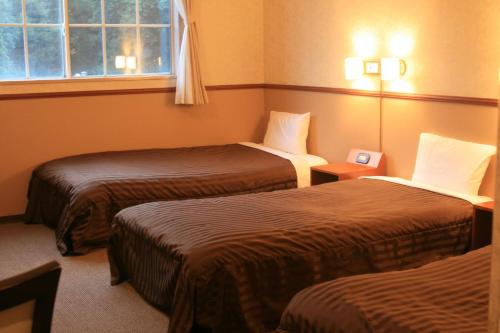 a hotel room with two beds and a window at Atami Hotel Paipuno Kemuri in Atami