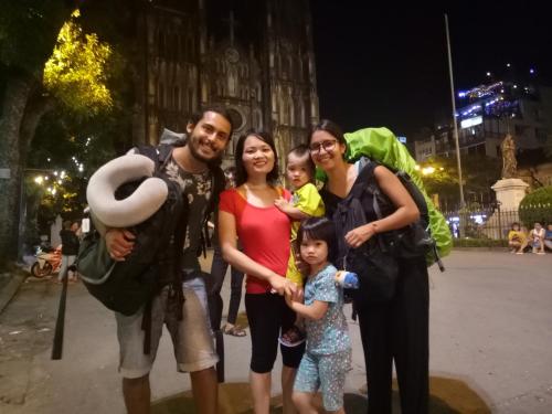 a family posing for a picture in front of a building at Nusmile's Hostel and Travel in Hanoi