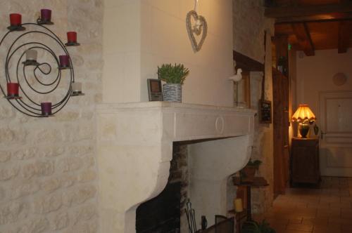 a living room with a fireplace with areath on the wall at Hôtel du Donjon in Aulnay