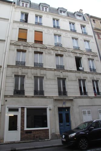 ein weißes Gebäude mit Fenstern und einem Auto vor dem Haus in der Unterkunft Well located apartment in Paris in Paris