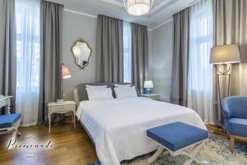 a bedroom with a large white bed and a blue chair at Villa Promenade in Burgas City