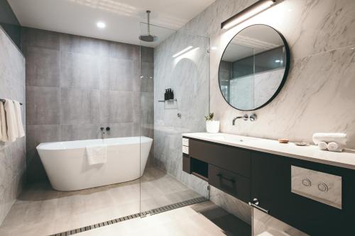 a bathroom with a tub and a sink and a mirror at Maylands Lodge in Hobart