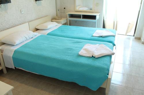 two beds in a room with blue sheets and white pillows at Esperides Hotel in Myrtos