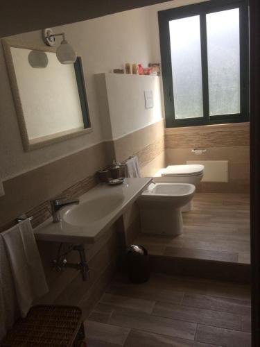 a bathroom with a sink and a toilet and a window at Casa Daniela in Patti