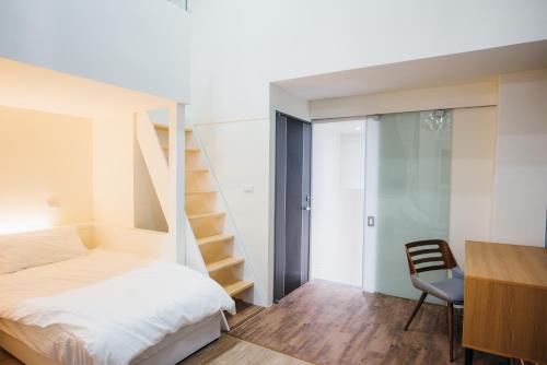 sypialnia z łóżkiem, biurkiem i schodami w obiekcie 放個Jia w mieście Taidong